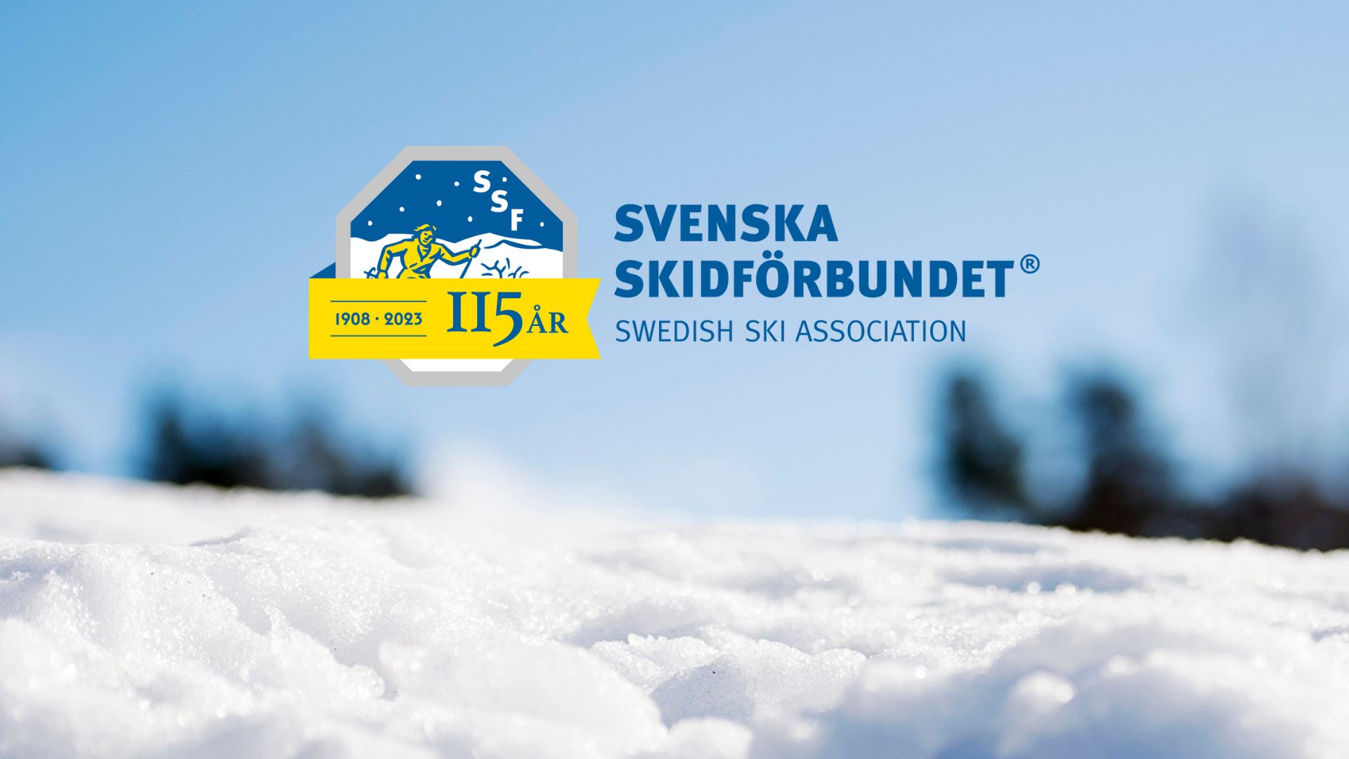 Snö och blå himmel med SSFs logotyp försedd med band som visar 115 år.