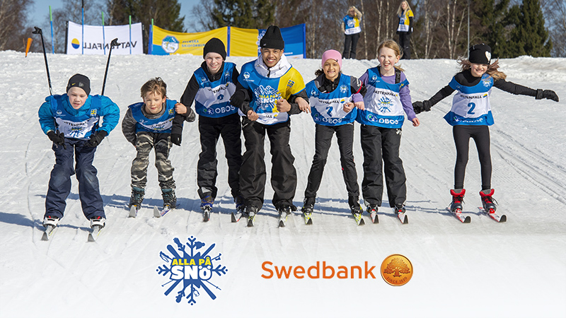 Glada barn åker skidor, längst ned visas Alla på snös och Swedbanks logotyper. Foto: Ulf Palm.